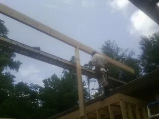 Carpenter setting a ridge beam over a new addition frame — Ice Dam Removal by Roofing Brothers in Caliente