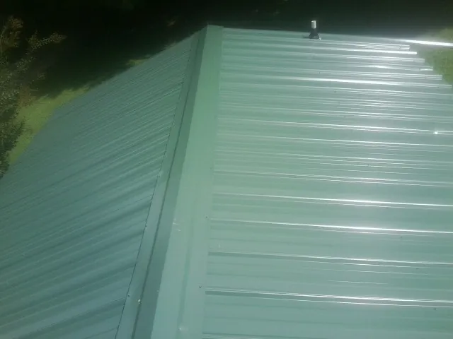 New green metal panels meeting at the ridge of a roof — Flat Roof Repair work by our crew in Caliente