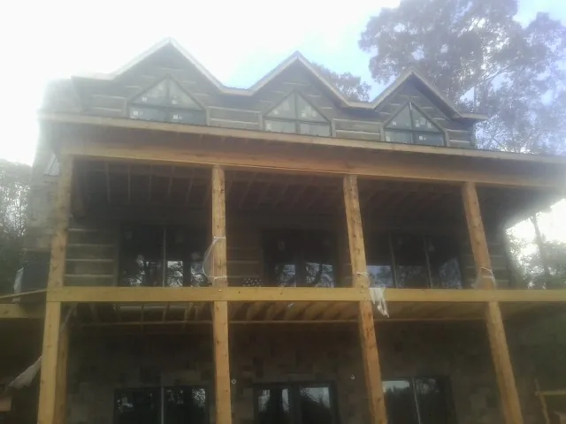 Dormers and porch framing on a large log home under construction — Roof Coating work by our crew in Caliente