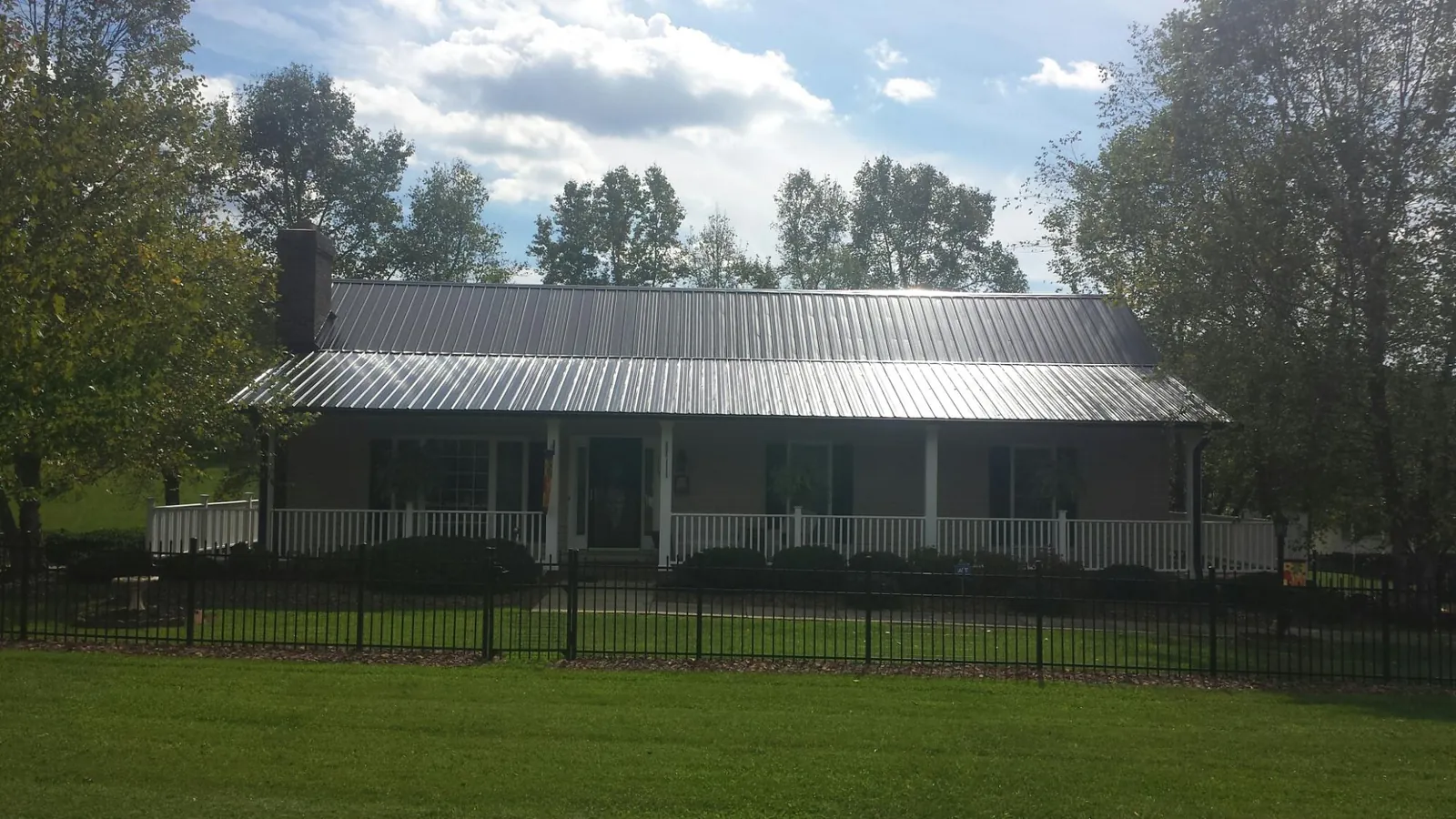 Gray metal roof on a brick ranch with a full width front porch — Gutter Guard Installation work by our crew in Caliente